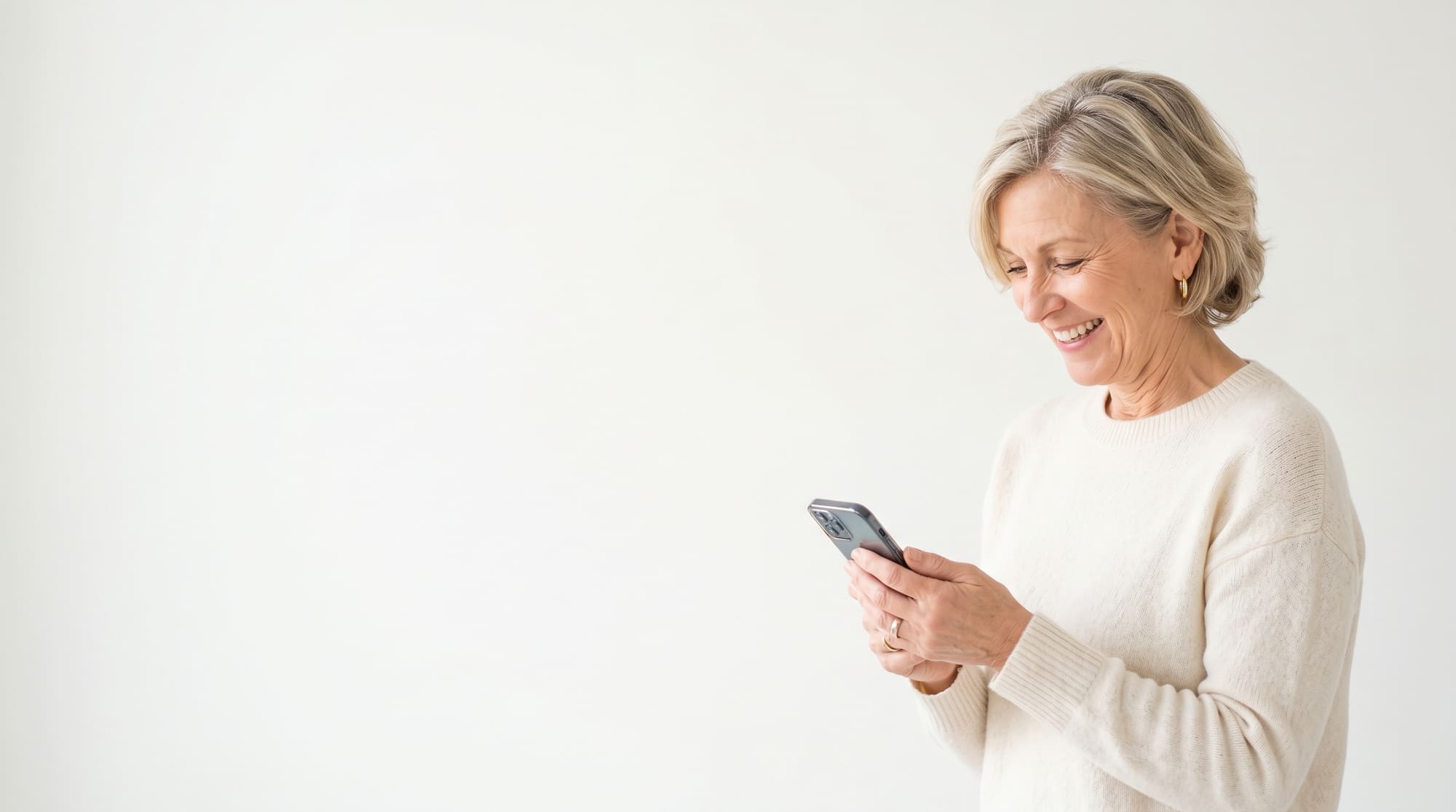 A smiling woman looking at her phone during a call